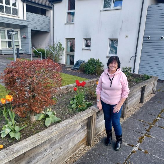 Tenant Mary Marshall standing in front of flower beds in a communal garden in Methlan Park