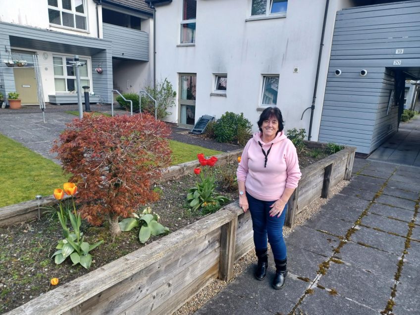 Tenant Mary Marshall standing in front of flower beds in a communal garden in Methlan Park