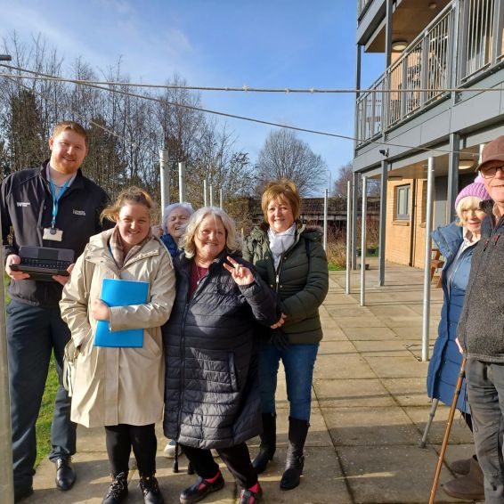 A group of customers and staff outside in the garden area of Beardmore Street, Dalmuir standing in the new seated patio area