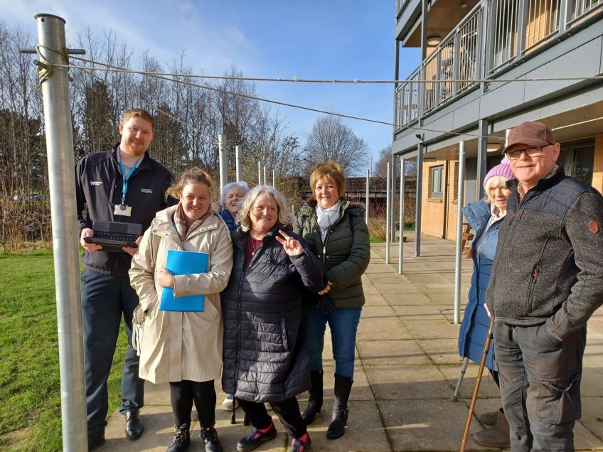 A group of customers and staff outside in the garden area of Beardmore Street, Dalmuir standing in the new seated patio area